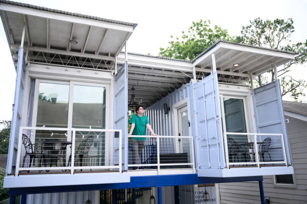 A man stepping onto the upper balcony of a modern container-style tinyhomes-us tiny home