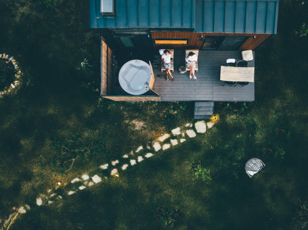 Aerial view of a couple relaxing on the deck of their Nestcraft tiny home beside a hot tub